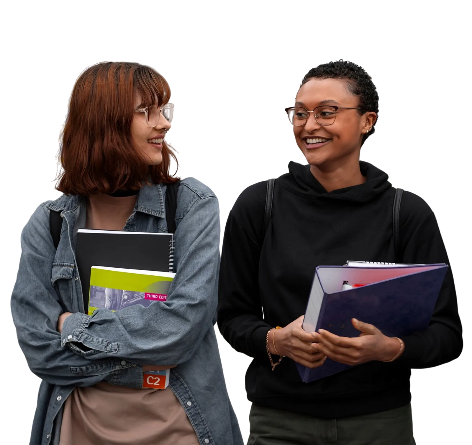 Two students discuss their learning while carrying books and folders as part of a skills program.