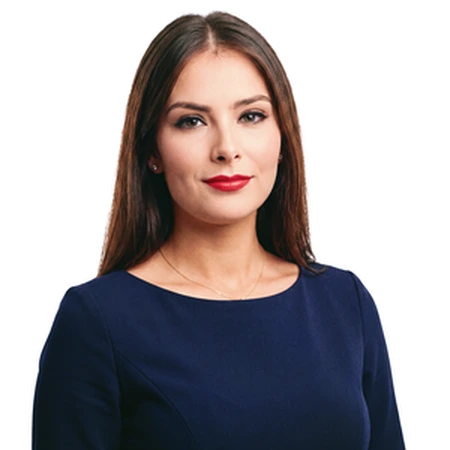 A professional portrait of Sahiba wearing a navy dress and red lipstick.