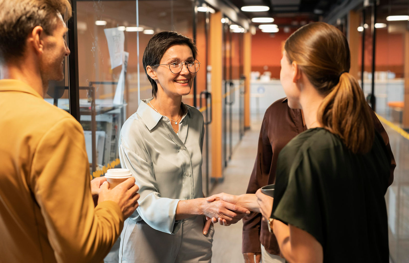 Business professionals shake hands, demonstrating positive workplace connections and employability skills.